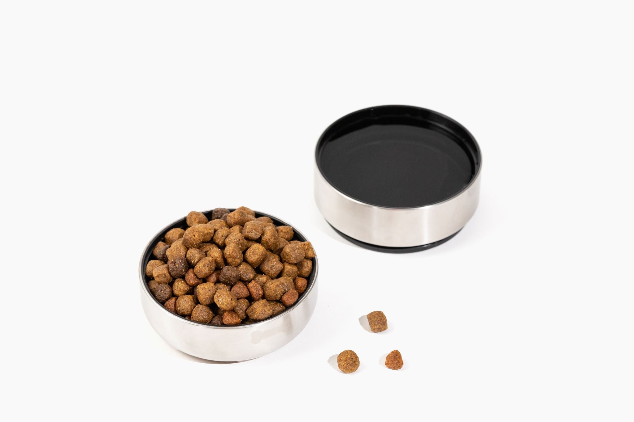 Two detachable stainless steel bowls from the Pup Pak dog water bottle, one filled with kibble and the other with water. These bowls are designed for convenience, allowing pet owners to provide food and hydration for their pets during travel and outdoor activities. The durable and portable design makes it easy to keep pets nourished and hydrated on the go.